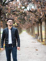Fototapeta na wymiar young man with glasses walking in a tunnel of trees