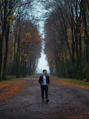 Fototapeta na wymiar young man with glasses walking in a tunnel of trees