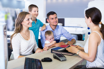 Young smiling family choosing material for mattress with saleswoman