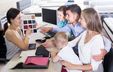 Obraz premium saleswoman in furniture store helping young family in choice of mattress material