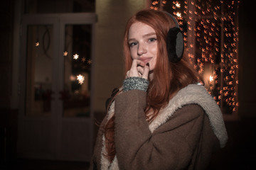 The portrait of an young redhear lady on the evening wearing earmuffs