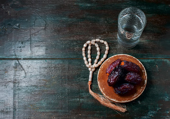 Dates fruit and rosary still life, on a dark wooden background.