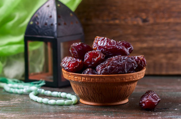 Dates fruit and rosary still life, on a dark wooden background.