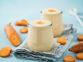 Yogurt with carrot. Vegetable yogurt. Two glass jar with yellow orange yoghurt or milkshake and...