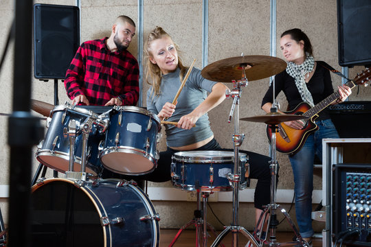 Music band with positive girl drummer rehearsing
