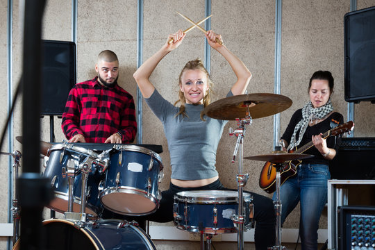 Music band with glad girl drummer rehearsing
