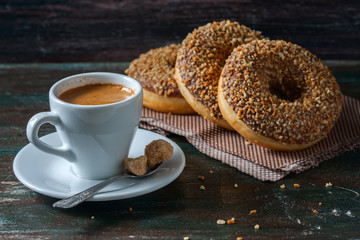 Coffee and homemade donuts with chocolate and nuts on a dark wooden background.