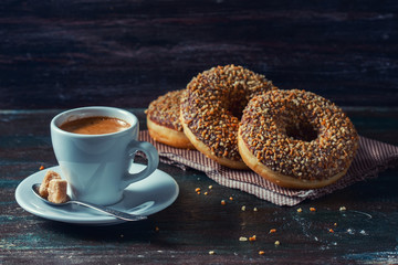 Coffee and homemade donuts with chocolate and nuts on a dark wooden background.