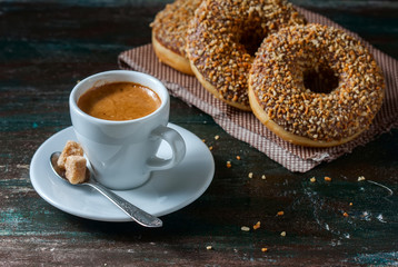 Coffee and homemade donuts with chocolate and nuts on a dark wooden background.