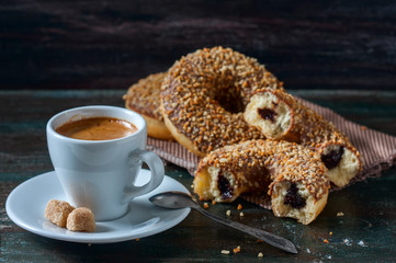Coffee and homemade donuts with chocolate and nuts on a dark wooden background.