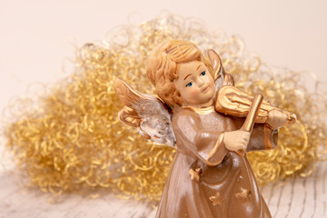Fototapeta premium Angel with violin in front of golden hair on white wood as Christmas background