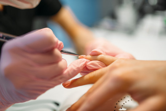 Beautician applying nail varnish to female client