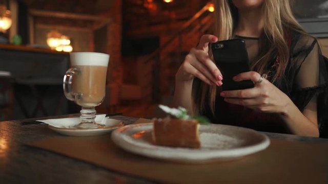 beautiful emotional happy girl is making photo of food in cafe, latte on the table, dessert ice cream chocolate cake cherry mint, communication in social networks