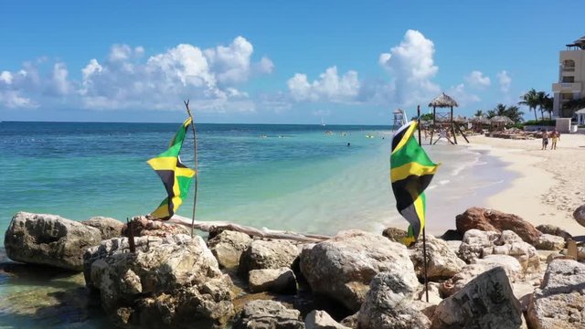 Aerial footage of jamaican flags on a beautiful tropical caribbean beach on Jamaica