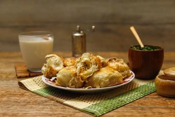Traditional Bosnian pastry- manti borek with meat on wooden table with yogurt. rustic background with low light and old bowls.