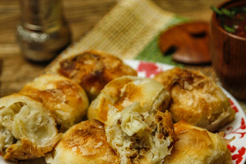 Traditional Bosnian pastry- manti borek with meat on wooden table with yogurt. rustic background with low light and old bowls.