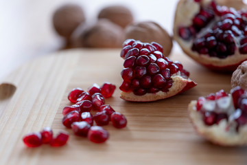 The pomegranates and with fruits and nuts on the wooden plate