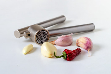 Peeled and unpeeled garlic cloves and metal hand garlic press