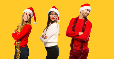 A group of people Blonde woman dressed up for christmas holidays looking over the shoulder with a smile on yellow background