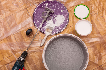 Paint brush, sponge roller, paints, waxes and other painting or decorating supplies on white wooden planks, top view