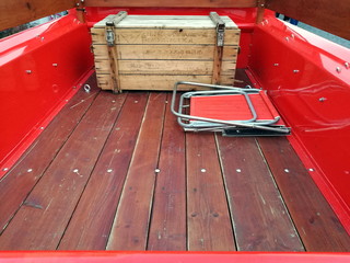 Ladefläche mit Holzkiste und Campingstuhl eines amerikanischen Pick-up der Sechzigerjahre in Rot...