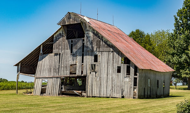 An aging and decaying wooden barn in a rural area. 