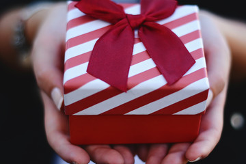 Female hands holding a gift box, present.