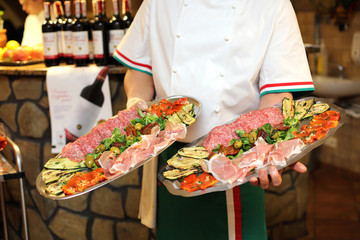Kelner trzyma w dłoniach talerze z jedzeniem w restauracji, katering. - obrazy, fototapety, plakaty