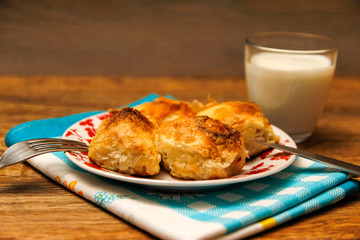 Traditional Bosnian pastry- manti borek with cheese on wooden table with yogurt. rustic background with low light and old bowls.