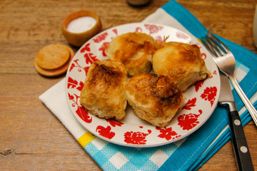 Traditional Bosnian pastry- manti borek with cheese on wooden table with yogurt. rustic background with low light and old bowls.