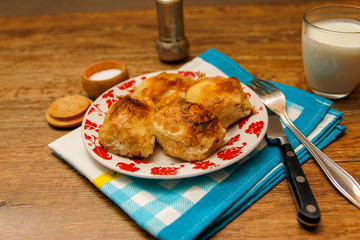 Traditional Bosnian pastry- manti borek with cheese on wooden table with yogurt. rustic background with low light and old bowls.