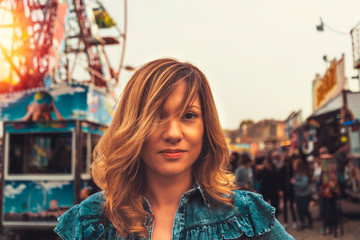 Lovely young woman in a Luna Park shortly before sunset in autumn