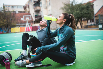 Young man with prosthetic leg enjoying with his friend at basketball court.