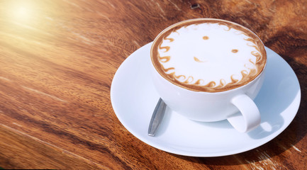 White cup of coffee art patterns on wood floors. Cappuccino art in a white cup and saucer on a wooden background.