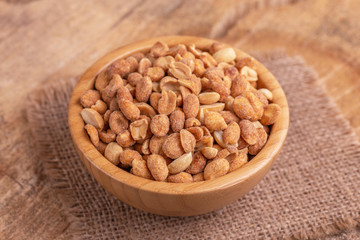 Roasted peanuts in wooden bowl on burlap napkin