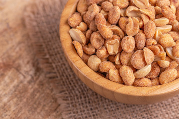 Roasted peanuts in wooden bowl on burlap napkin