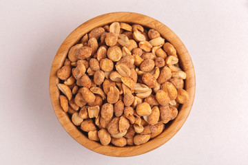 Roasted peanuts in wooden bowl on light marble background
