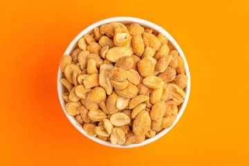 Roasted peanuts in paper cup on bright orange background