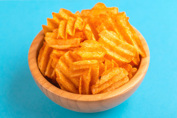 Crispy corrugated potato chips in wooden bowl