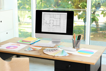 Designer's workplace with computer and paint color palette samples on table