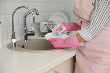 Woman doing washing up in kitchen sink, closeup view. Cleaning chores