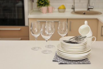Clean dishes, glasses, cups and cutlery on table in kitchen
