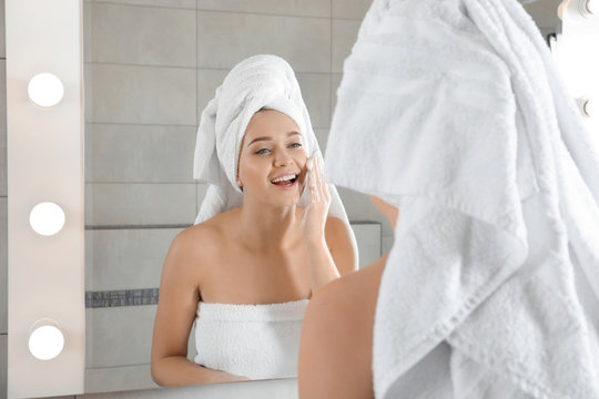 Young Woman Washing Face With Soap Near Mirror In Bathroom