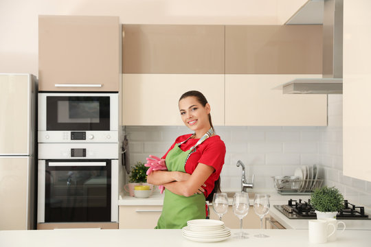 Beautiful young woman with clean dishes in kitchen