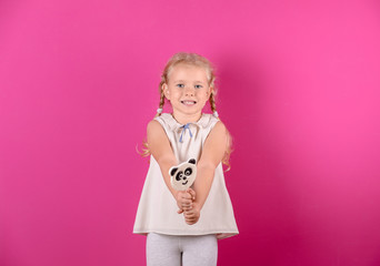 Cute little girl with candy on color background