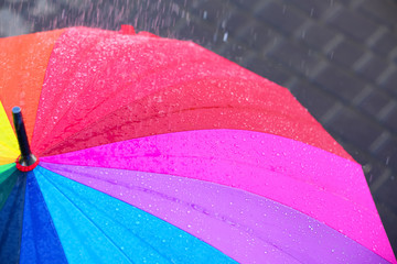 Bright color umbrella under rain outdoors, closeup