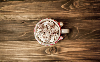 Cappuccino with marshmallows in a mug on a woolen scarf