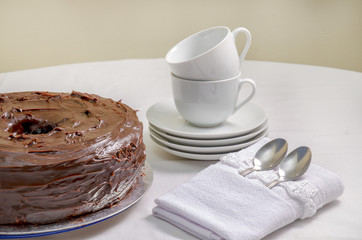 Freshly baked of homemade chiffon chocolate cake. Chocolate cake and white dishes and spoons  on white background, close up.
