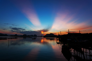 Fototapeta na wymiar morning sunrise light at coastal fishing village,Beautiful scenery morning sunrise over sea and mountain in phang - nga thailand
