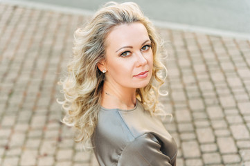 Outdoor portrait of beautiful woman with blond curly hair, top view